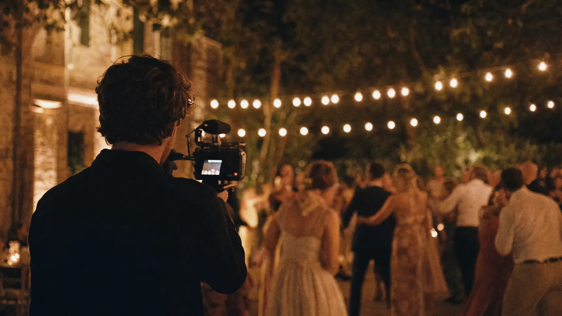 Second cinematographer filming the dance floor under string lights